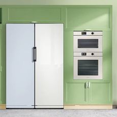 A blue and white customisable Samsung refrigerator and white grill and oven both built into green surrounds and cabinets