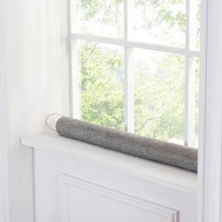 Gray draft blocker with taupe handle on white window sill with white crittal windows