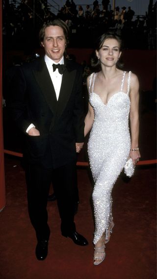 Elizabeth Hurley in a white beaded dress, standing next to Hugh Grant