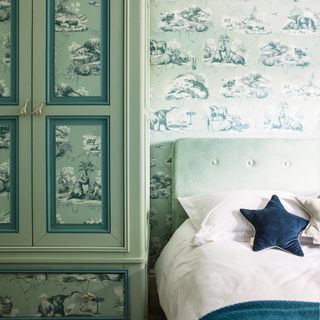 a classic child's bedroom with wallpaper on the walls and also on panelled sections of the wardrobe