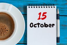 October 15th on a notepad with a pen, and a cup of coffee on a blue wooden background