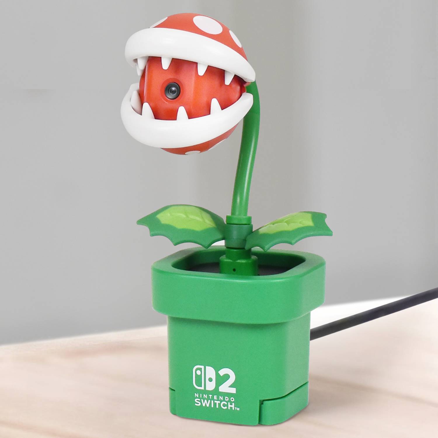 Official promo image of the Piranha Plant Switch 2 camera by Hori sitting on a wooden desk.