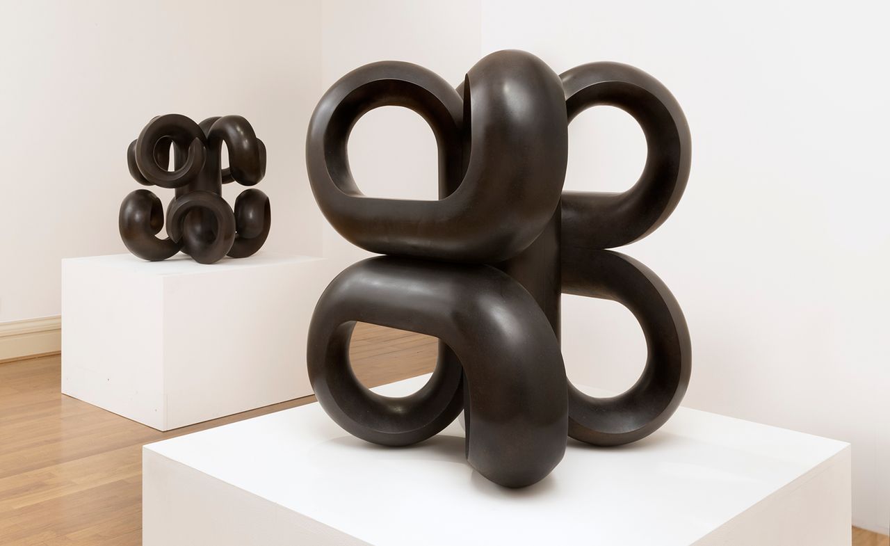 Black curvy sculptures on white podiums