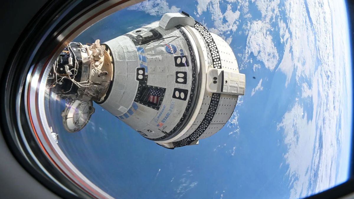 a white space capsule is seen through a window of the international space station, with earth in the background