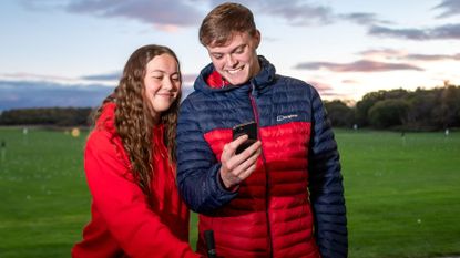Image of two golfers studying the Rules of Golf on a phone