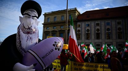Demonstrators hold Iranian flags and a huge inflated figure representing Iran's Supreme Leader Ali Khamenei holding a nuclear bomb as they protest against the Iranian regime in Germany