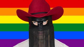 A press shot of Orville Peck on a pride flag background