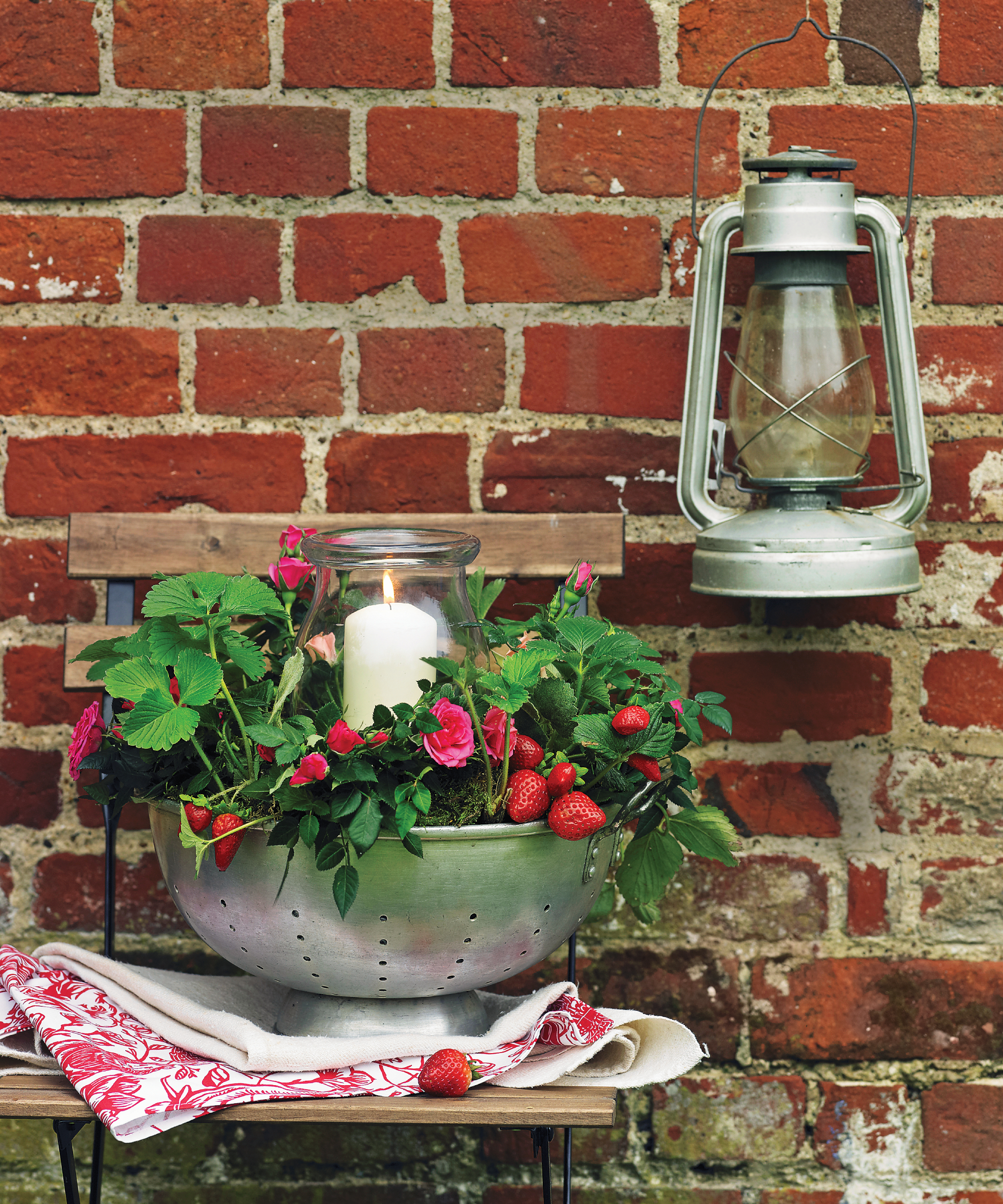 recycled colander used as a container for strawberries with a candle
