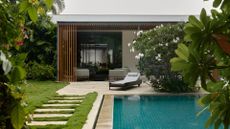A garden with a pool, a sun lounger, and flowering trees