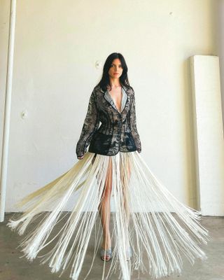 Woman wears a vintage blazer and fringe skirt from Arcade Vintage Co-op.