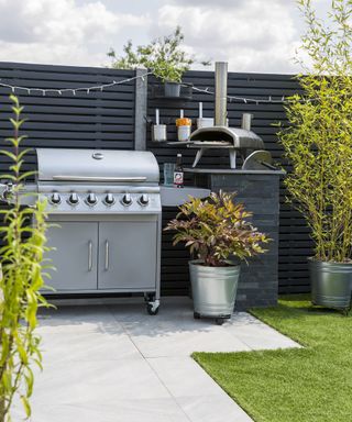 A small outdoor kitchen area with a gas grill and pizza oven