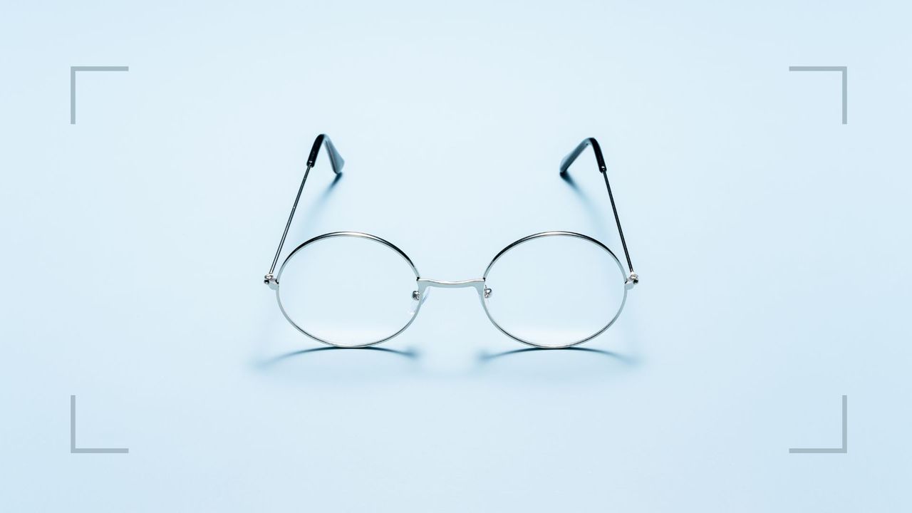 Pair of wire framed glasses sitting on a surface, representing the question of how often should you have an eye test