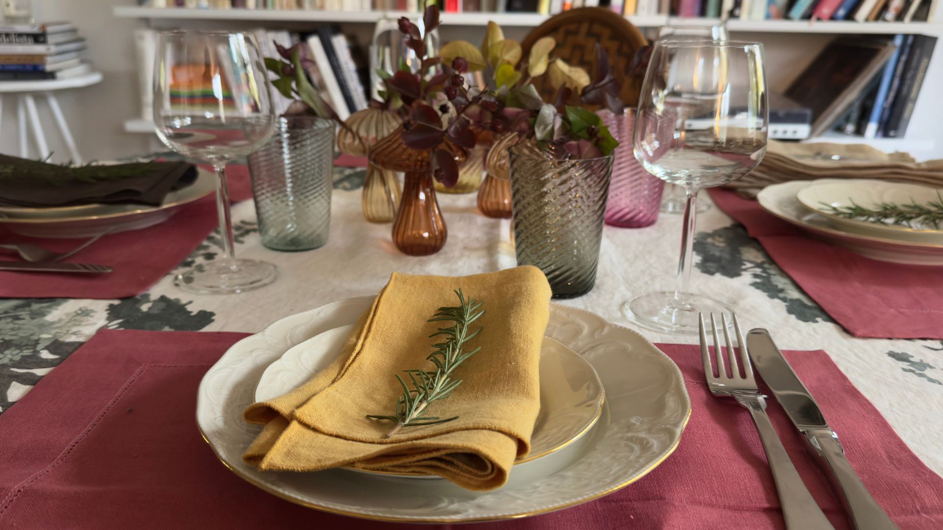 Table setting with plates and colored glassware, red place mats and yellow napkins