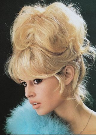 Brigitte Bardot with a bouffant hairstyle and a blue boa in 1960.