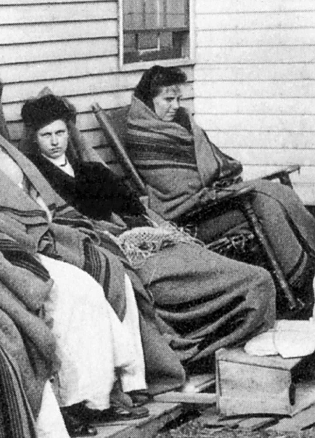 A black and white photo of Mary Mallon wrapped in a blanket on the left