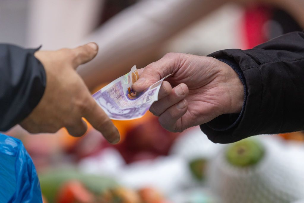 UK GDP growth represented by two people exchanging a £20 note