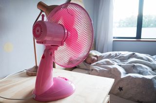 pink desktop fan in child's bedroom while child sleeps in bed