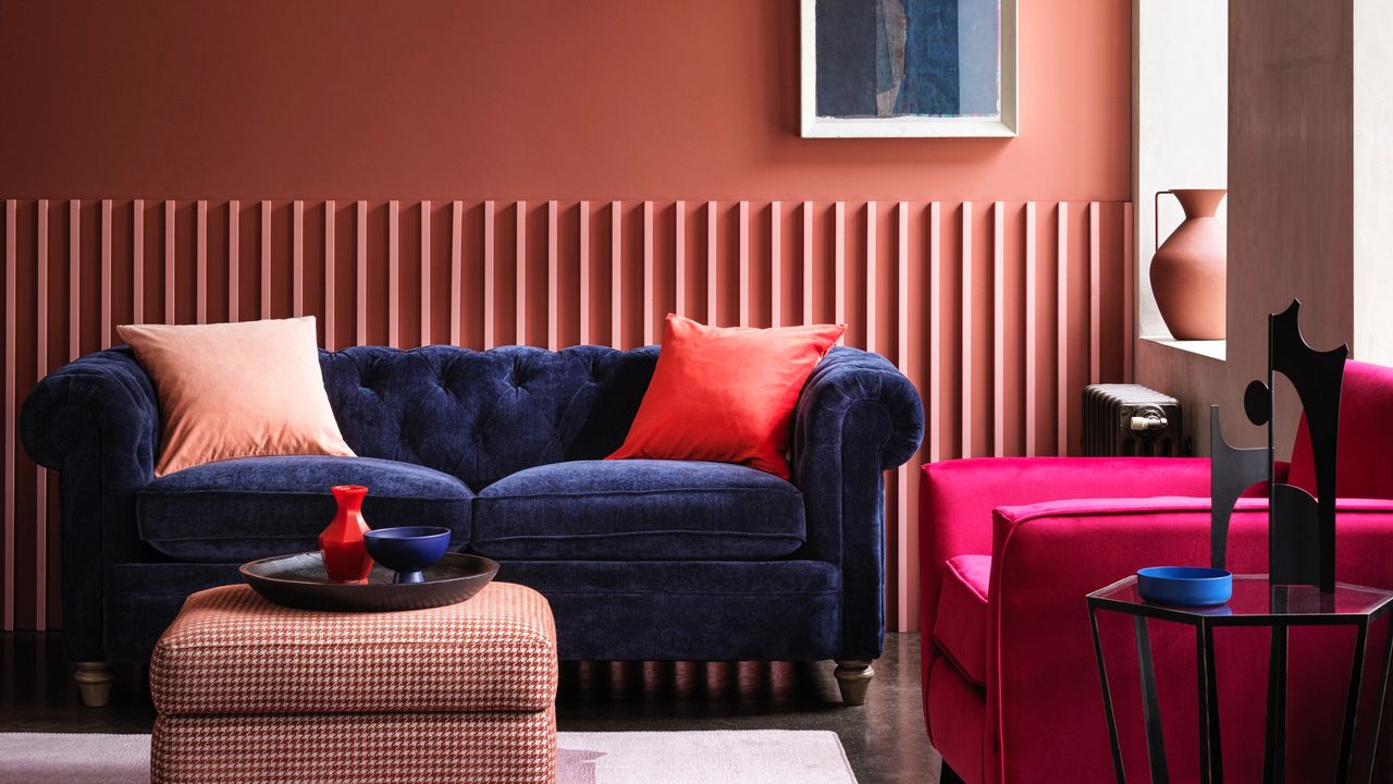 living room colour mistakes, coral living room with blue velvet sofa, bright pink armchair, houndstooth footstool, artwork, black accents 