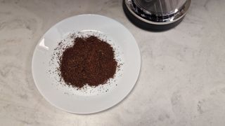 A plate of drip coffee grounds next to the KitchenAid Coffee Grinder