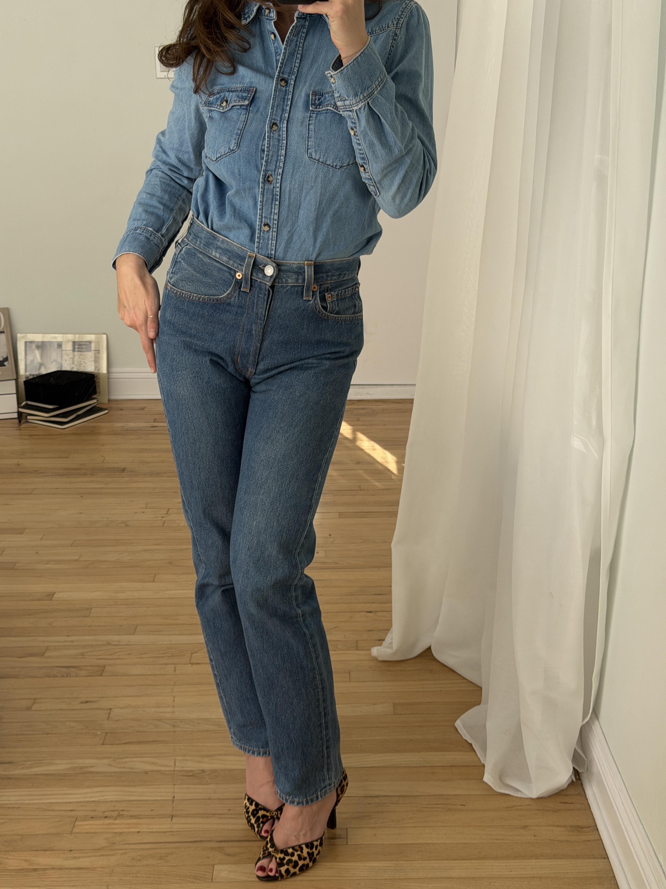 Kathryn Zahorak posing in mirror wearing denim shirt, jeans, and leopard heels