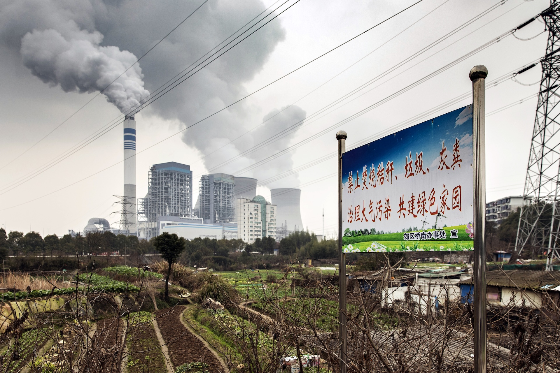 A photograph of a coal-powered power station with a Chinese sign in the foreground