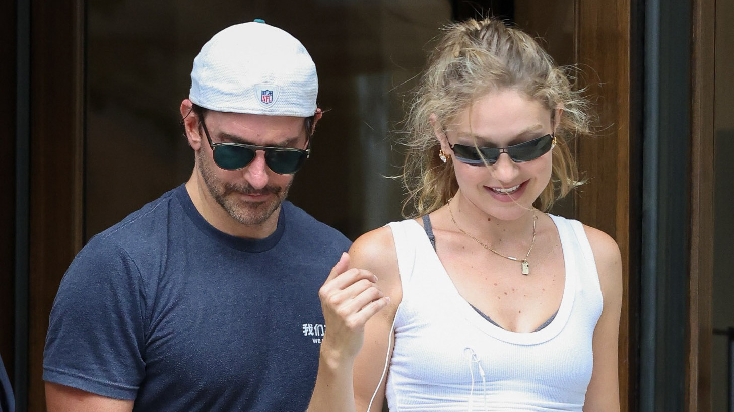 Gigi Hadid with Bradley Cooper in Paris, wearing a white tank top, gray leggings, and brown suede New Balance sneakers