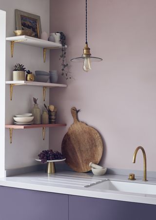 Kitchen painted in Annie Sloan paints, pink on walls, lilac doors, white countertop, brass tap, open shelving