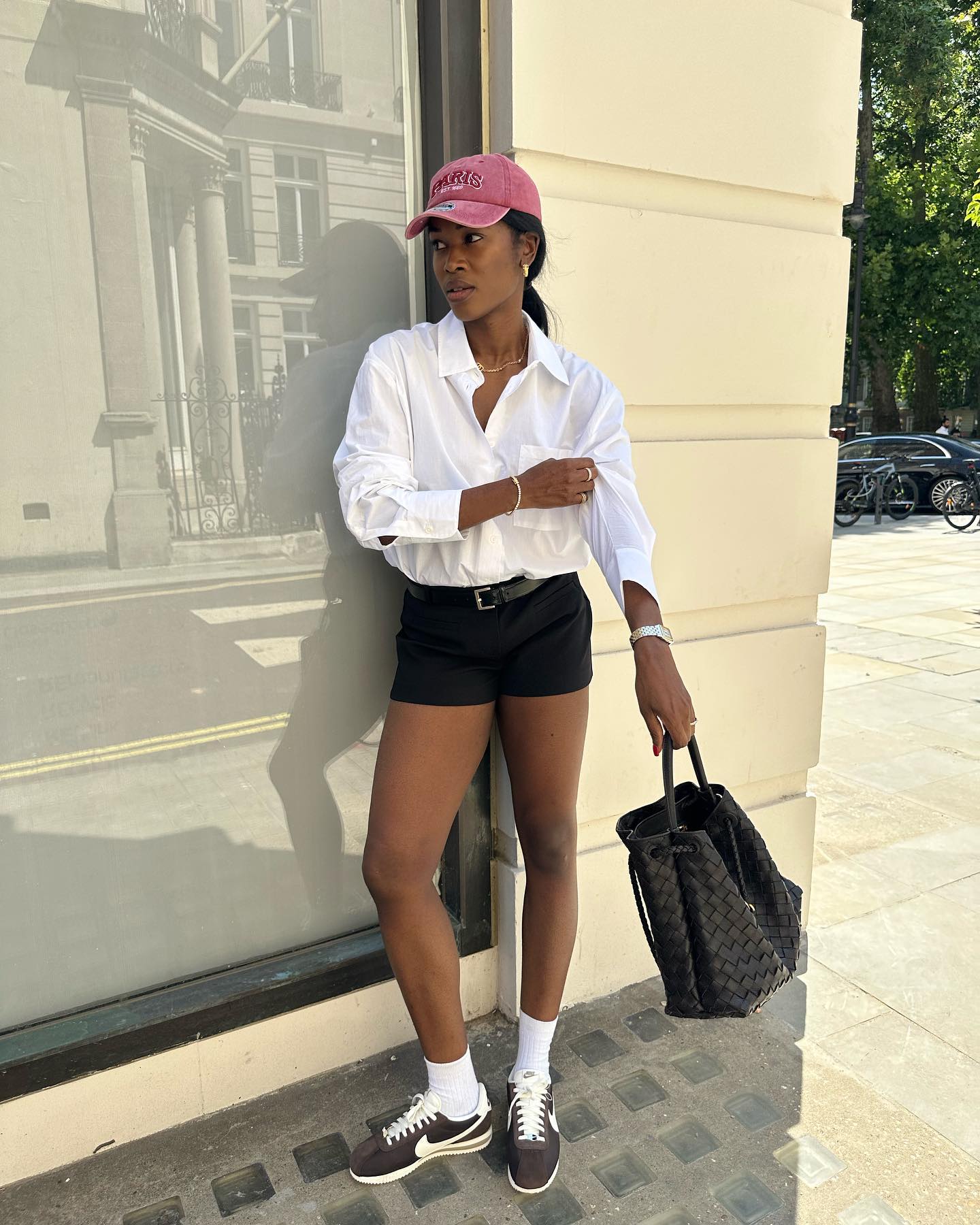 Woman in black shorts, white shirts, and retro Nike sneakers