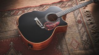 Harley Benton CLG-650SM-CE Black: the handsome but affordable cutaway acoustic isd photographed against a patterned rug on a wooden floor.