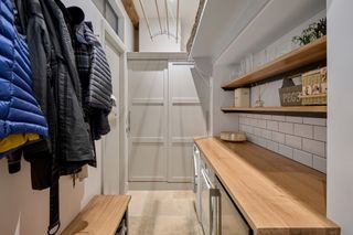 A utility room with wooden counter tops, coat pegs and shelving for extra storage