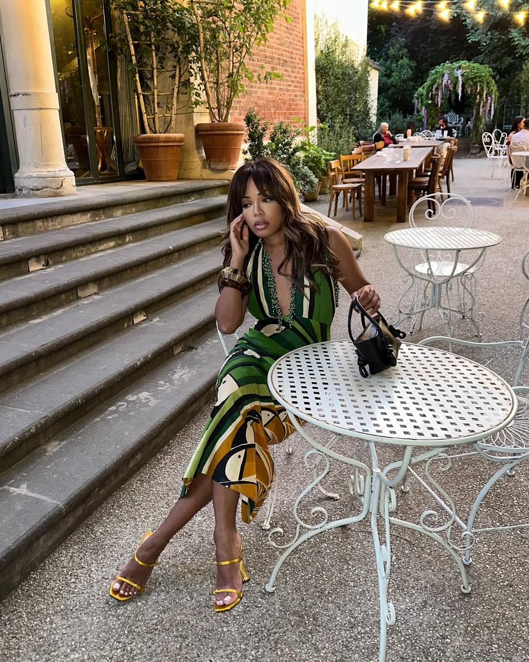 @slipintostyle wears metallic gold strappy heels with a green, cream and black printed midi dress