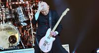 Billy Corgan holds his picking hand to his head as he holds a note on his Reverend signature model