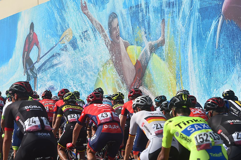 The peloton passes a mural Abu Dhabi Tour