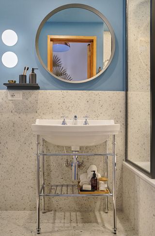 Francesca Venturoni's bathroom featuring blue walls, speckled tiles and round mirror