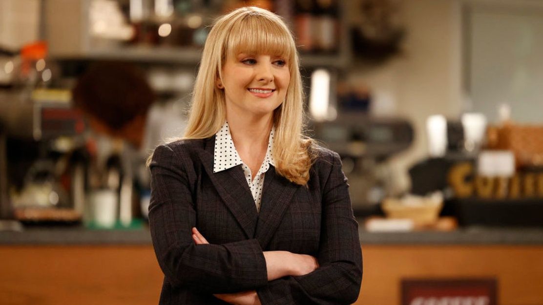 Judge Abby Stone (Melissa Rauch), the lead character in NBC sitcom Night Court season 2, poses with her arms crossed, wearing a dark grey suit and white polka dot shirt.