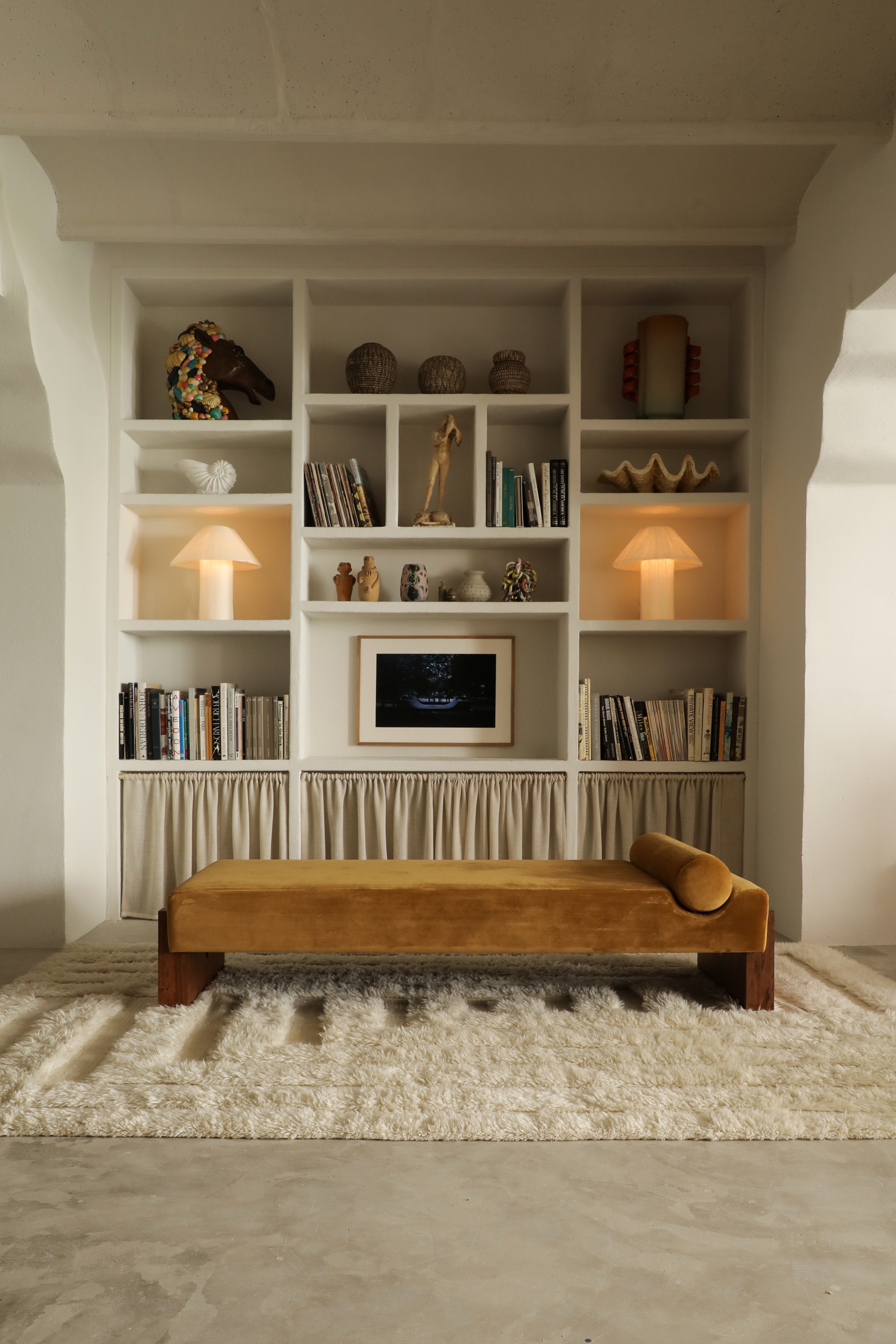 shelving with objects, art, and lamps with a day bed in front