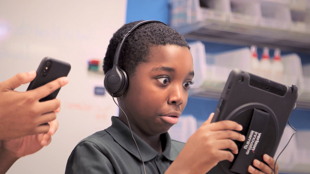 Child in classroom, amazed by AR tech.