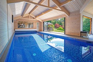 indoor pool with doors opening onto garden by Origin Leisure
