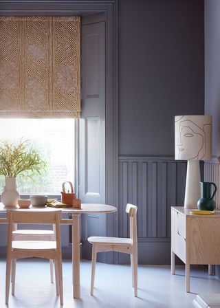 Dining room with table and chairs, grey paneled walls and detail lamp