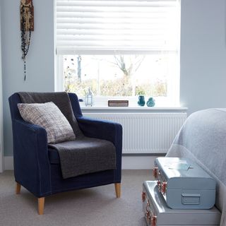 Blue bedroom with occasional chair and storage boxes