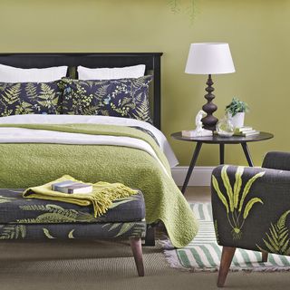bedroom with dark blue bed with leafy prints and carpet flooring