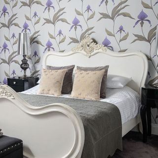 bedroom with floral wallpaper bed with designed cushion and lamp