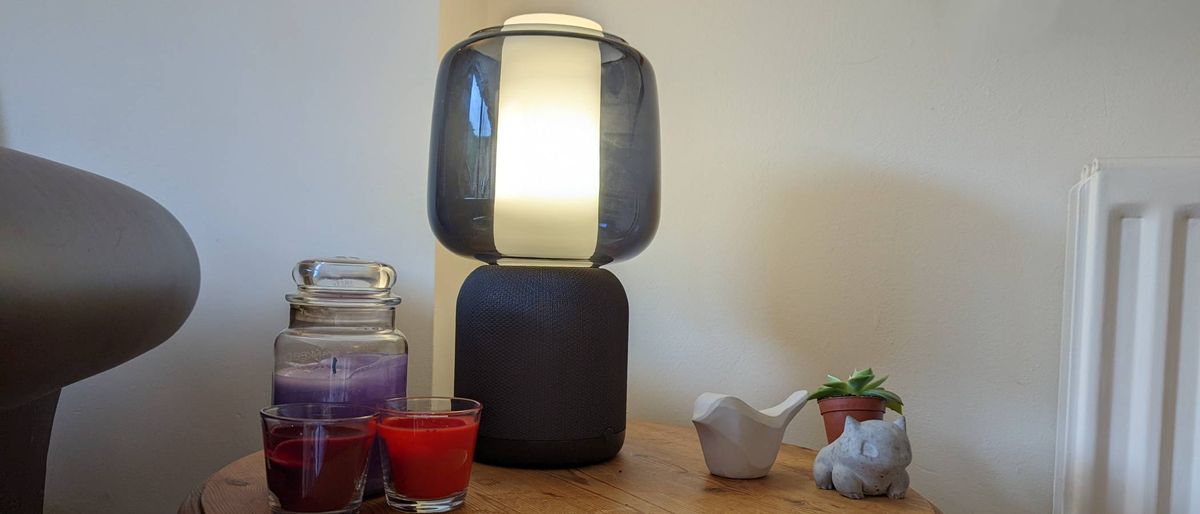 Symfonisk Table Lamp Speaker (Gen 2) on table with candles and a plant - it is turned on