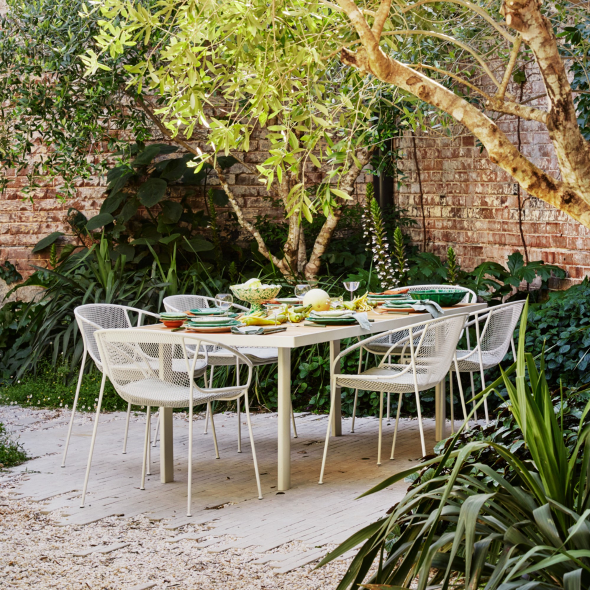 A garden with a King Living white outdoor dining table with a set of Luna garden chairs in white