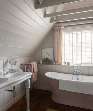 neutral coastal bathroom with pink cast iron bath and double vanity
