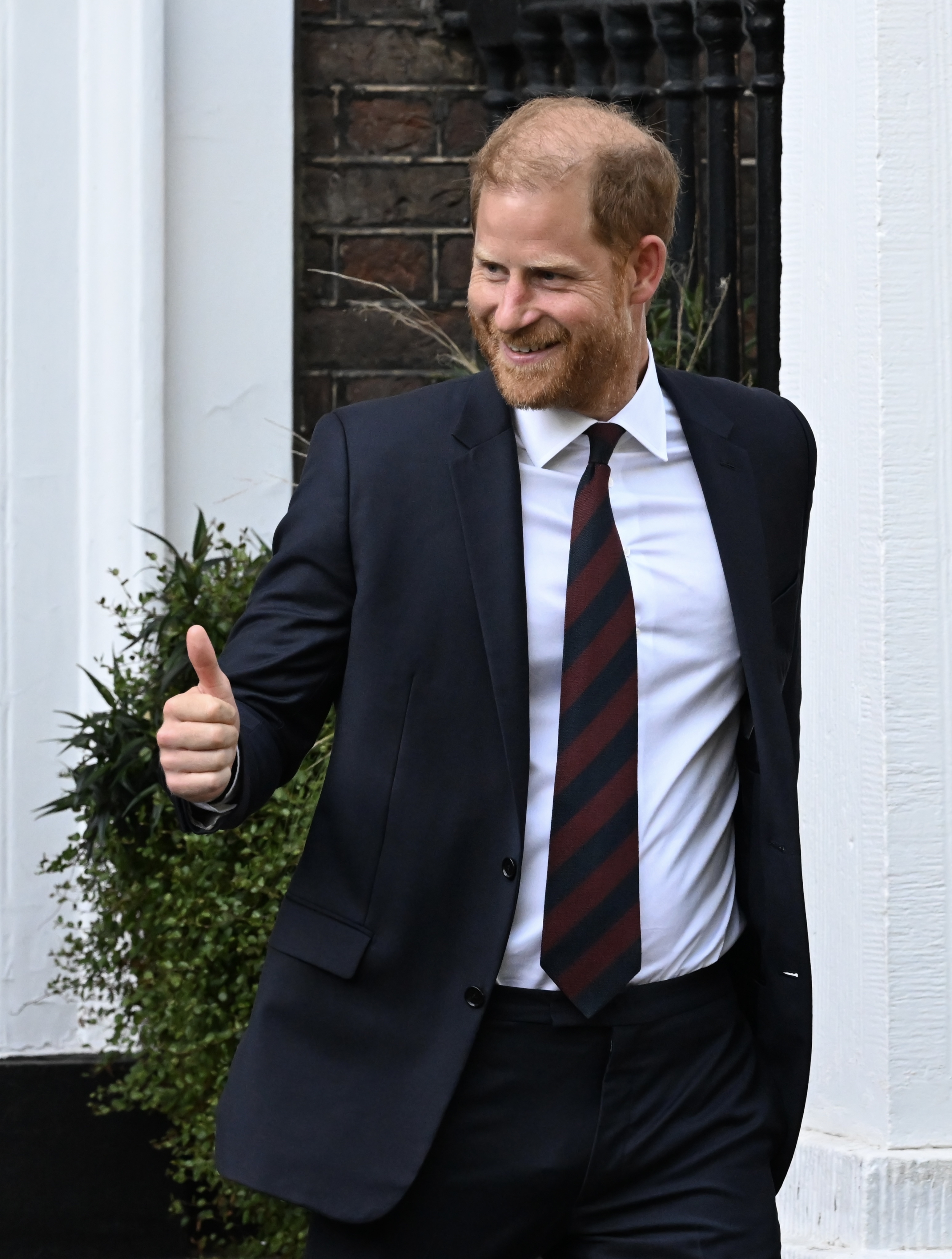 Prince Harry wearing a suit and tie giving a thumbs up