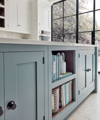 A light blue kitchen island with open bookshelves in the side