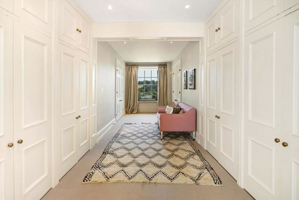 A white panelled wall hallway with large patterned rug