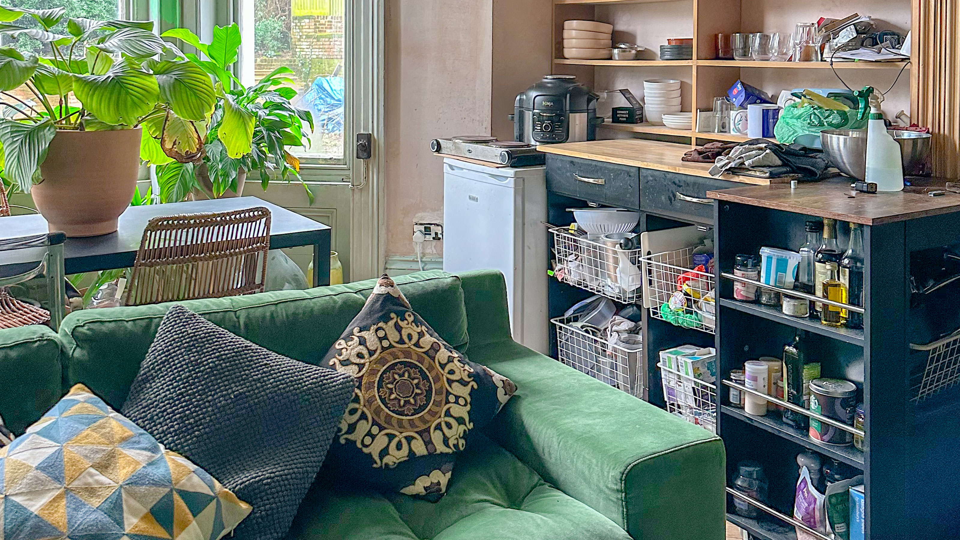 Temporary kitchen setup in living room behind green velvet sofa