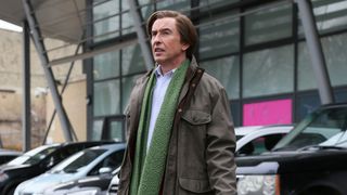 Alan Partridge wearing a coat and scarf, looking confused